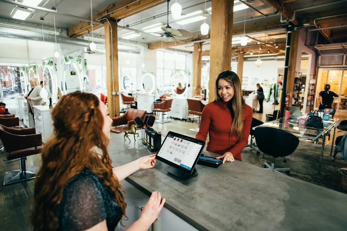 A shop owner checking her payments on a tablet at the counter